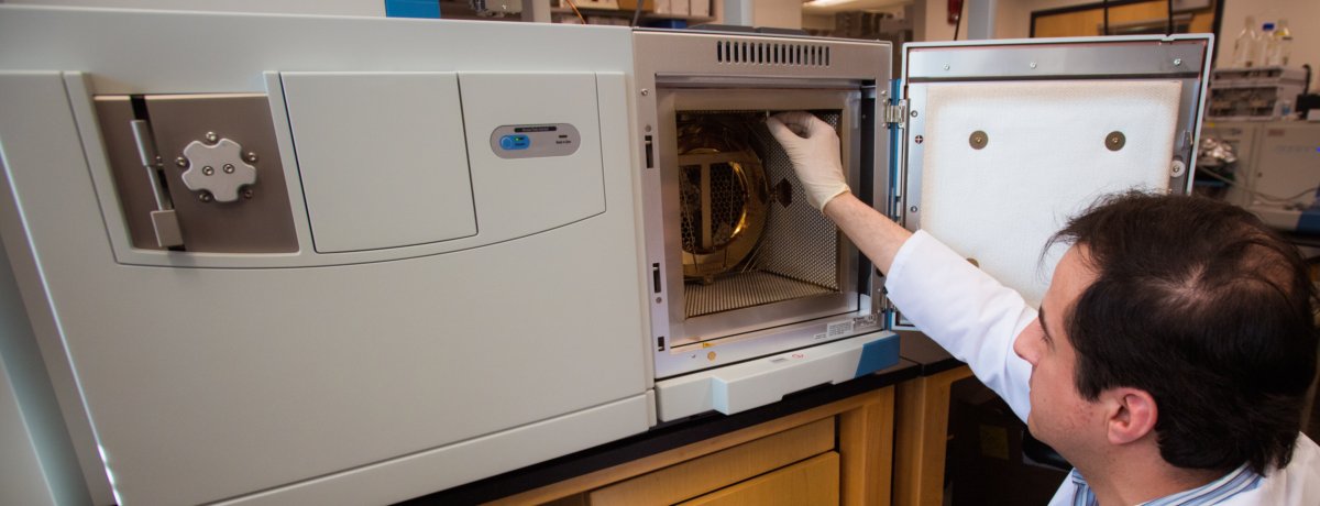 Scientist opening up the front panel of a mass spectrometer instrument