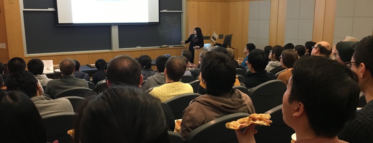 A postdoctoral fellow presents her research to other trainees as they enjoy a pizza lunch.